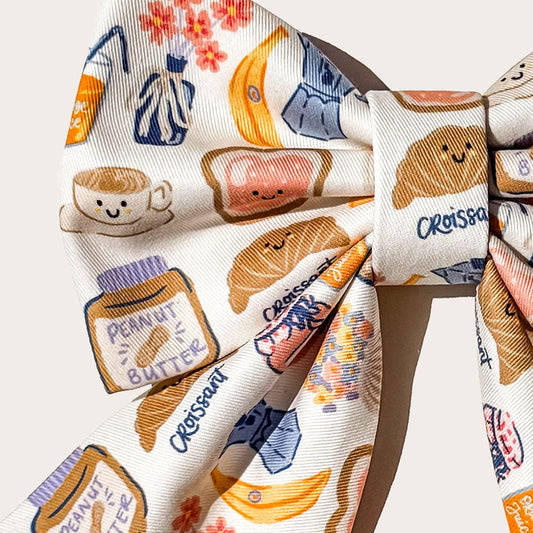 Close Up details featuring a whimsical breakfast food print with croissants, bananas, coffee cups, and peanut butter jars on a cream cotton fabric.