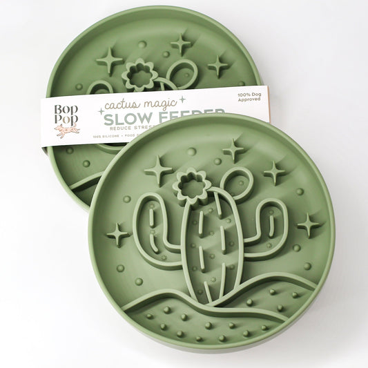 Cactus Magic Slow Feeder staggered on white background with upper left feeder displaying brand packaging labeled 'Cactus Magic SLOW FEEDER' and lower right feeder displaying 3 dimensional pattern of a cactus with blooming flower in the desert hill with 5 stars in sage green color.