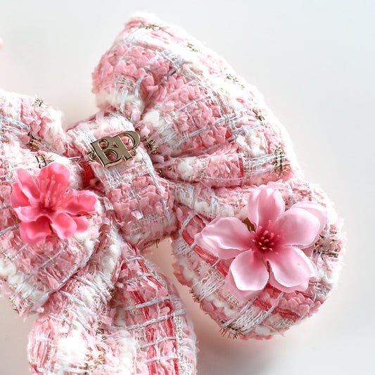Pair of pink and white baby shoes with floral decorations on a light background