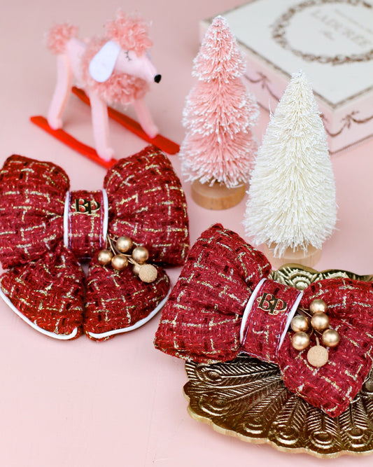 Tweed Burgundy Red decorative sailor bow and bow tie with gold holly accents on a pink table with small Christmas trees and a dog figurine. Holiday picture perfect dog accessory for christmas family portraits. Bop Pop Pets pet accessories