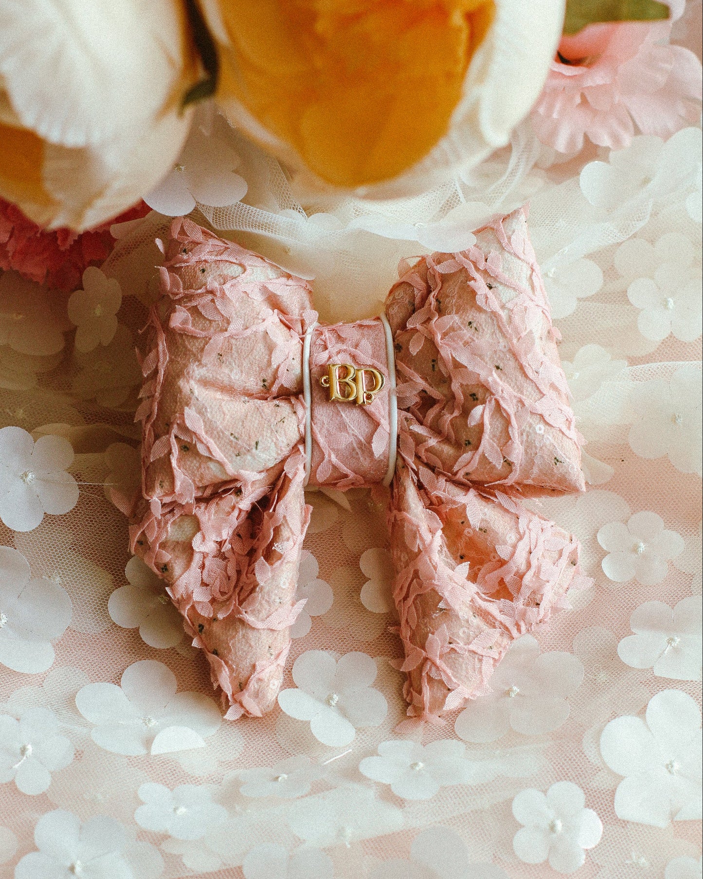 Pink hair bow with gold letter 'B' on a floral background