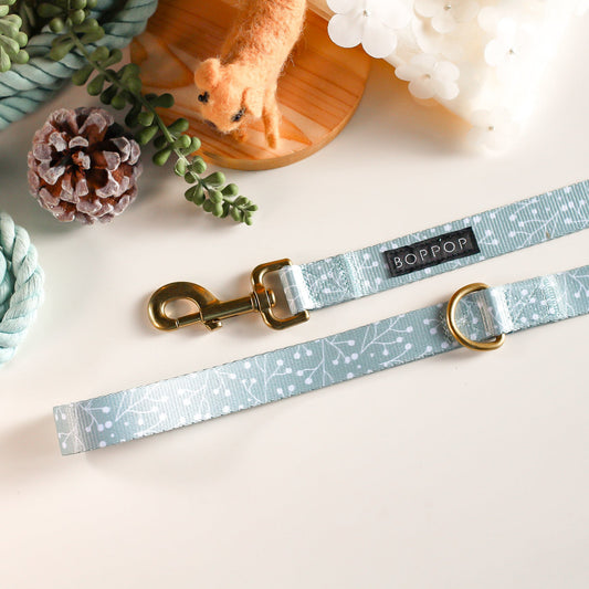 Dog leash with blue pattern and gold hardware on a light surface with decorative items.