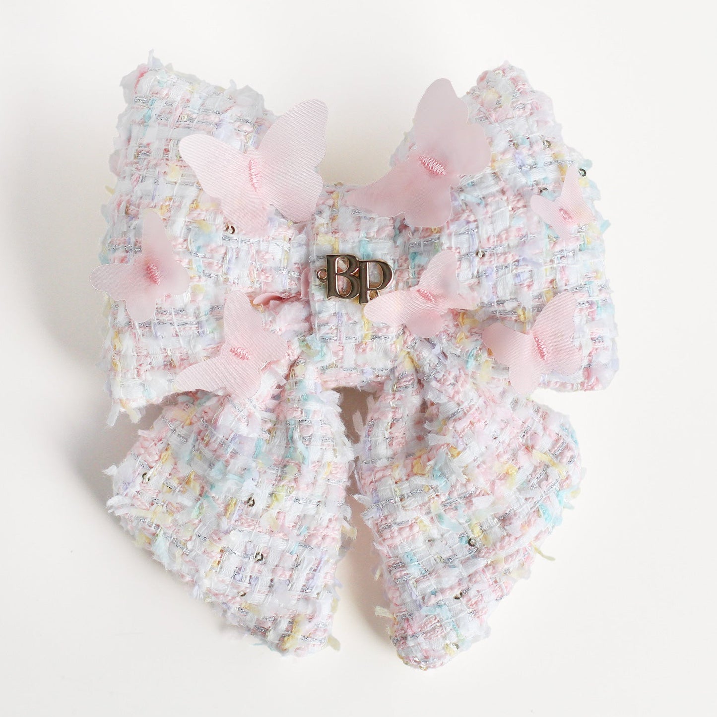 Decorative bow with pastel colors and a visible brand logo on a light background