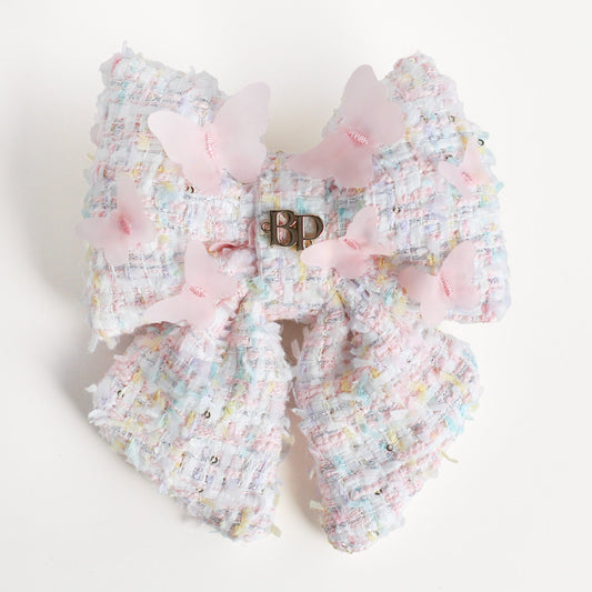 Decorative bow with pastel colors and a visible brand logo on a light background