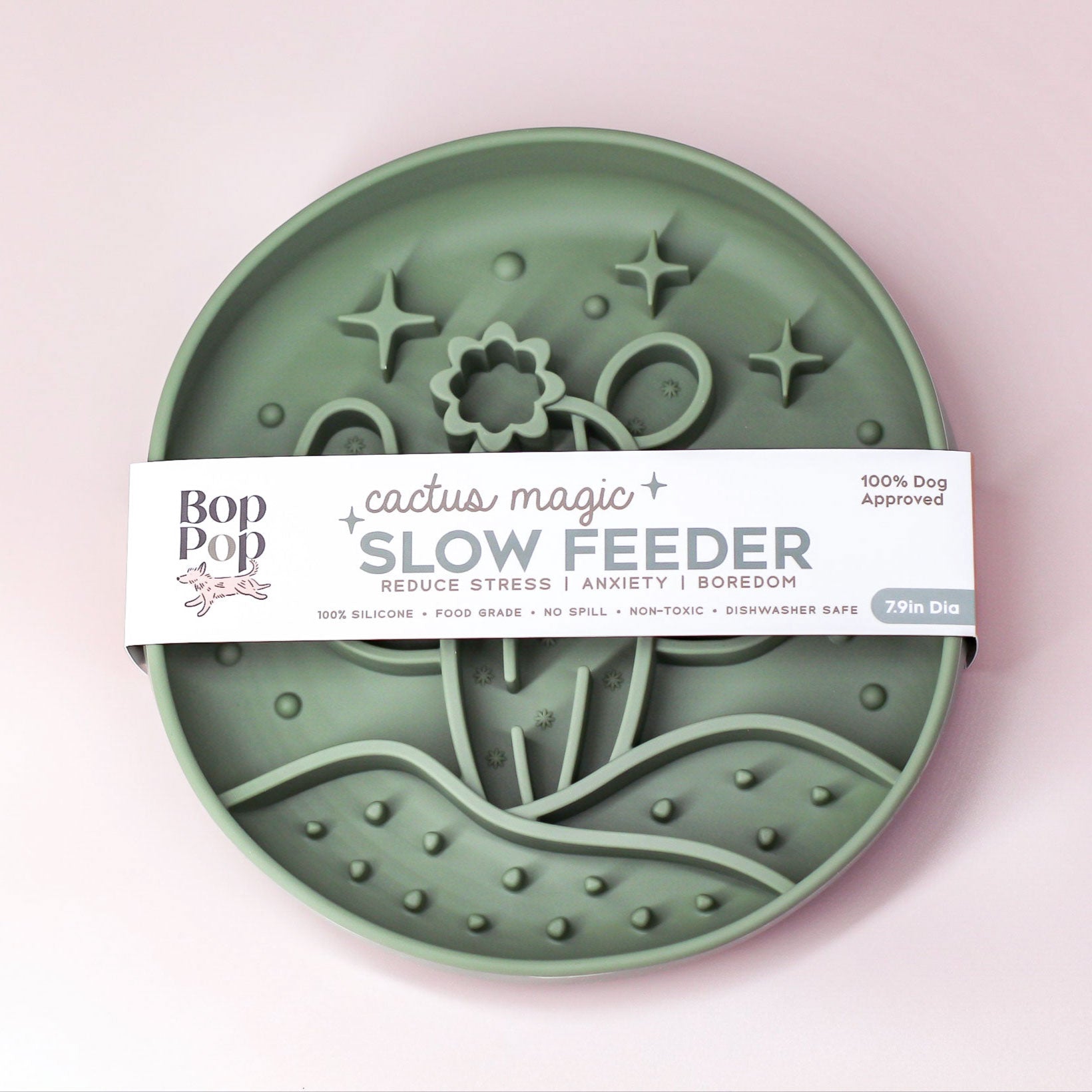 A round green slow feeder dog bowl by Bop Bop, wrapped in a white paper band labeled 'cactus magic SLOW FEEDER'. The feeder features raised patterns of cacti, stars, and flowers.