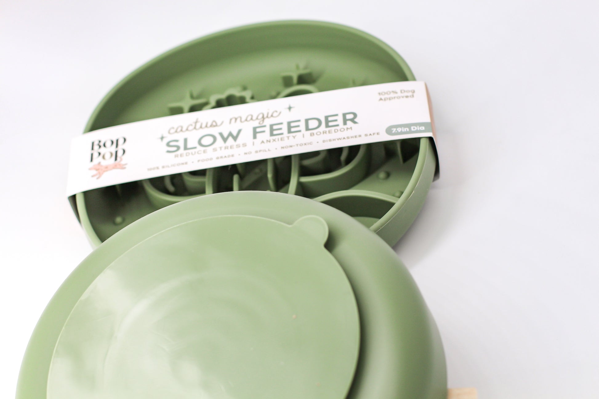 Cactus Magic Slow Feeder staggered on white background with upper feeder displaying blurred view of brand packaging labeled 'Cactus Magic SLOW FEEDER' and lower feeder displaying backside of smaller circle suction pad with a small half-circle tab on edge.
