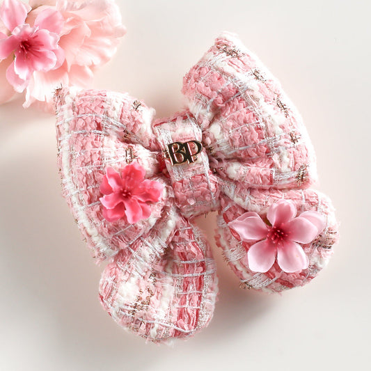 Pair of pink baby shoes with floral decorations on a white background