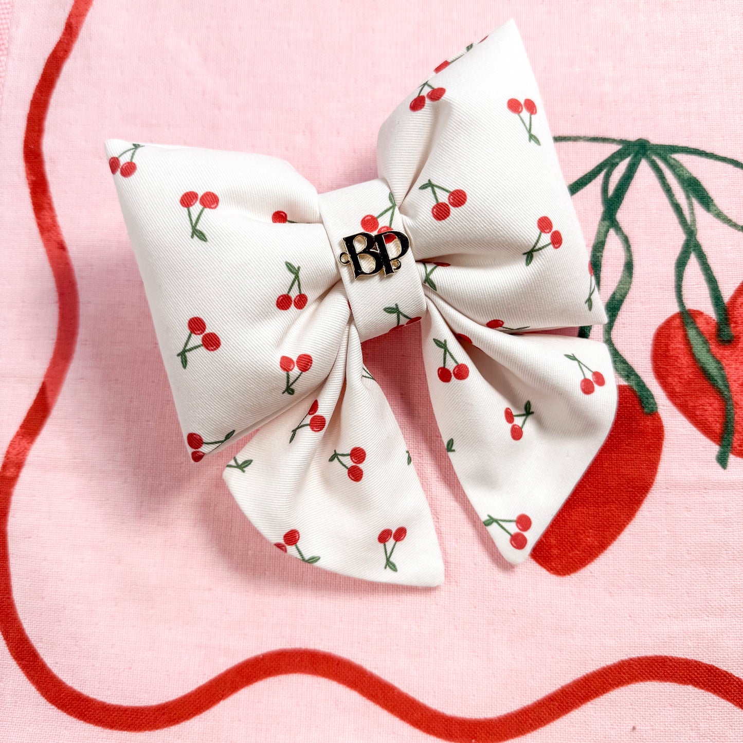 White bow with red cherry pattern on a pink background