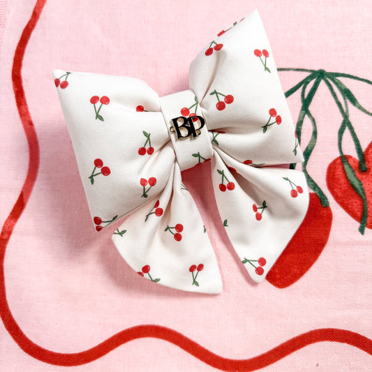White bow with red cherry pattern on a pink background