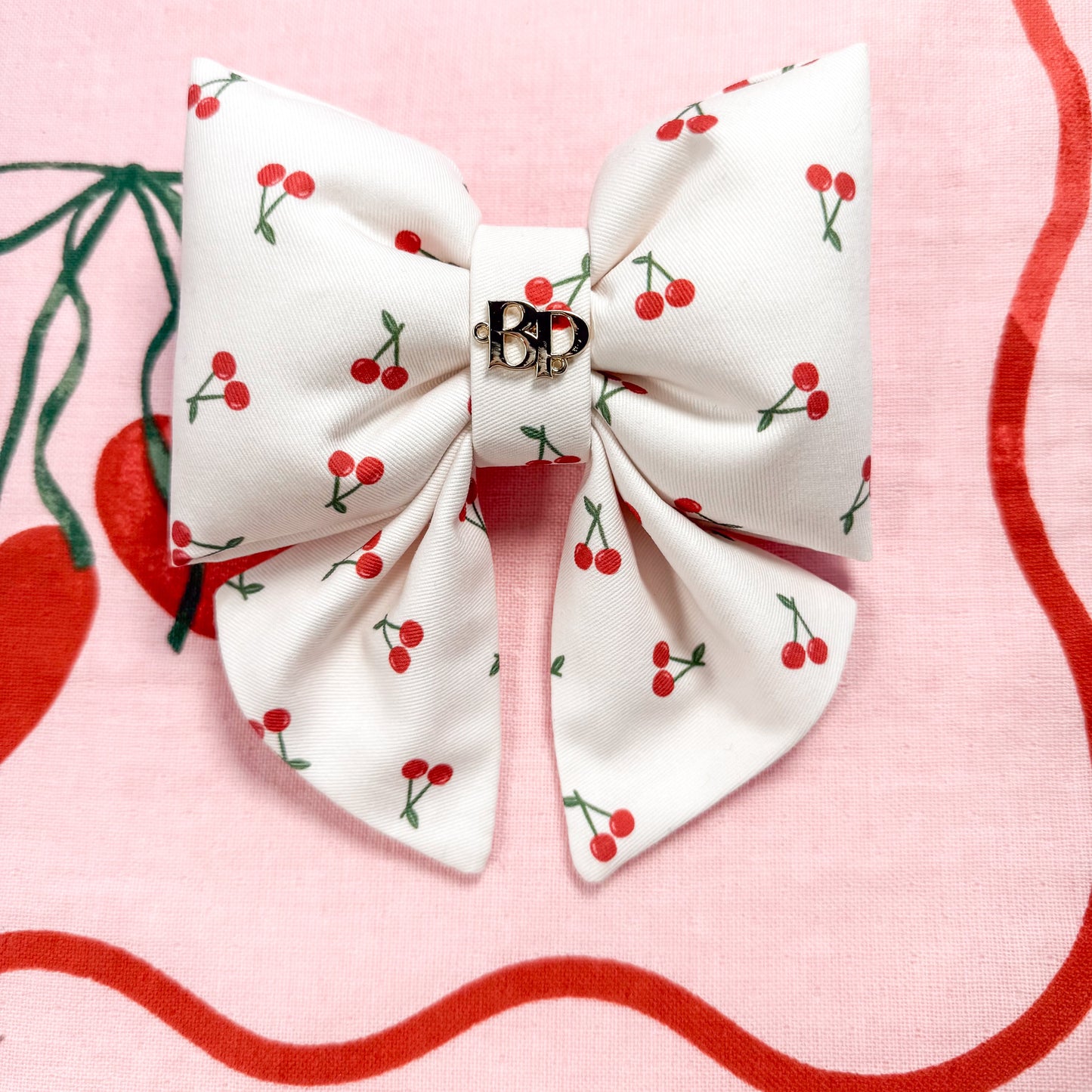 White dog bow with mini red cherry pattern on a pink background
