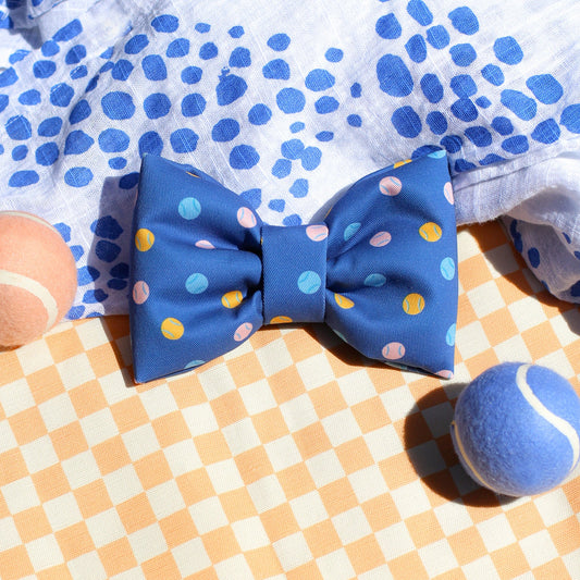 Blue bow tie with colorful tennis balls on a dog bow tie on a checkered fabric background