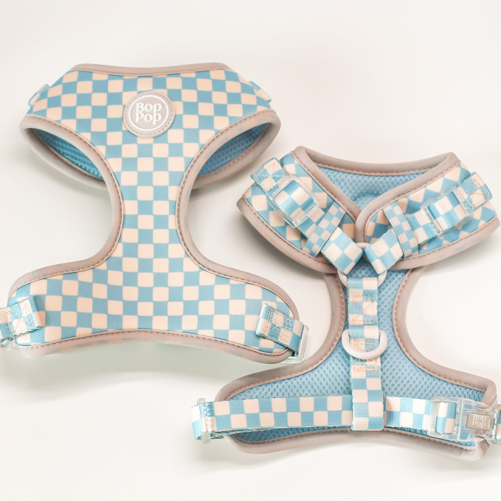Two checkered dog harnesses on a light background