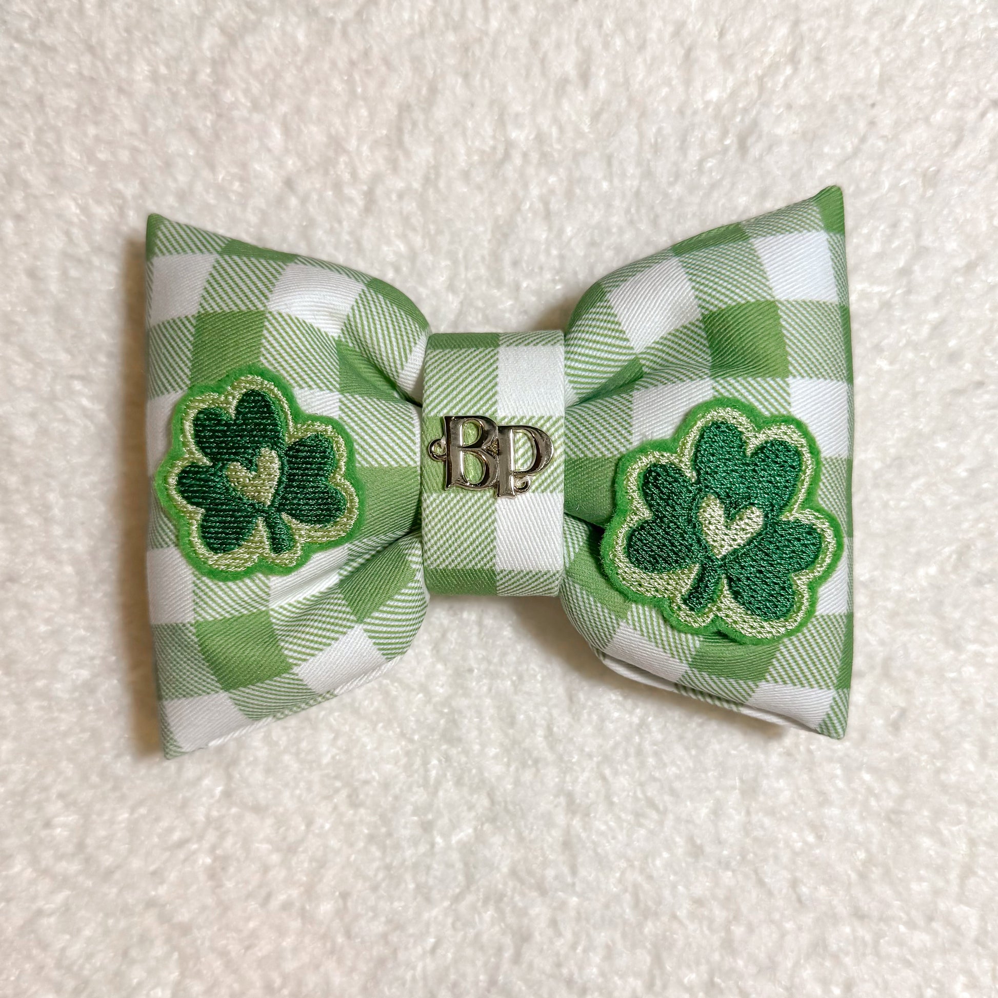 Green and white checkered bow with shamrock designs on a textured surface