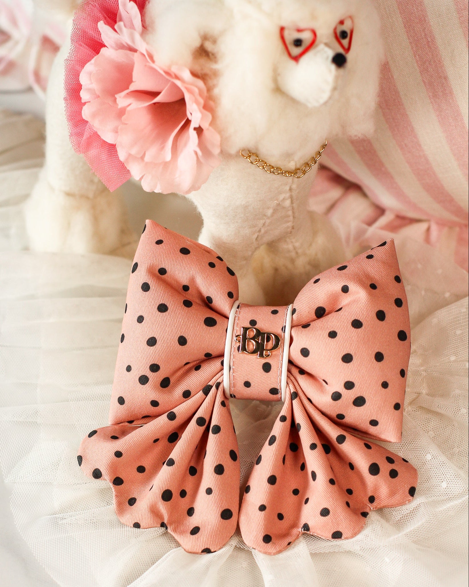 Pink polka dot bow with a brand logo on a fluffy white background