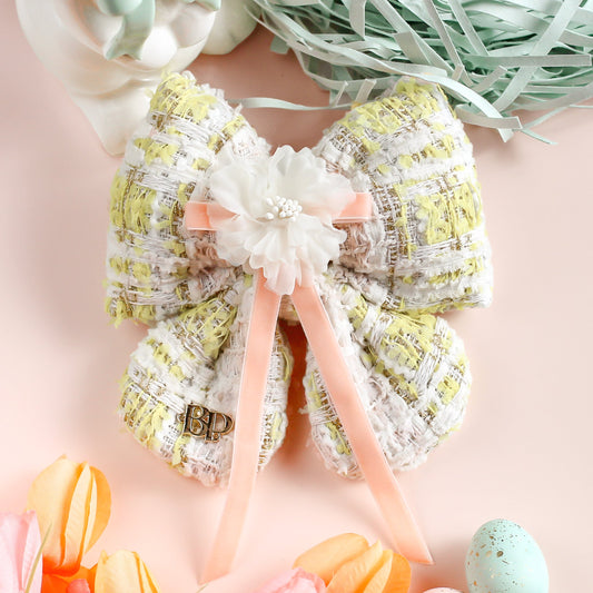 Decorative bow with pastel colors on a pink background with Easter-themed items.
