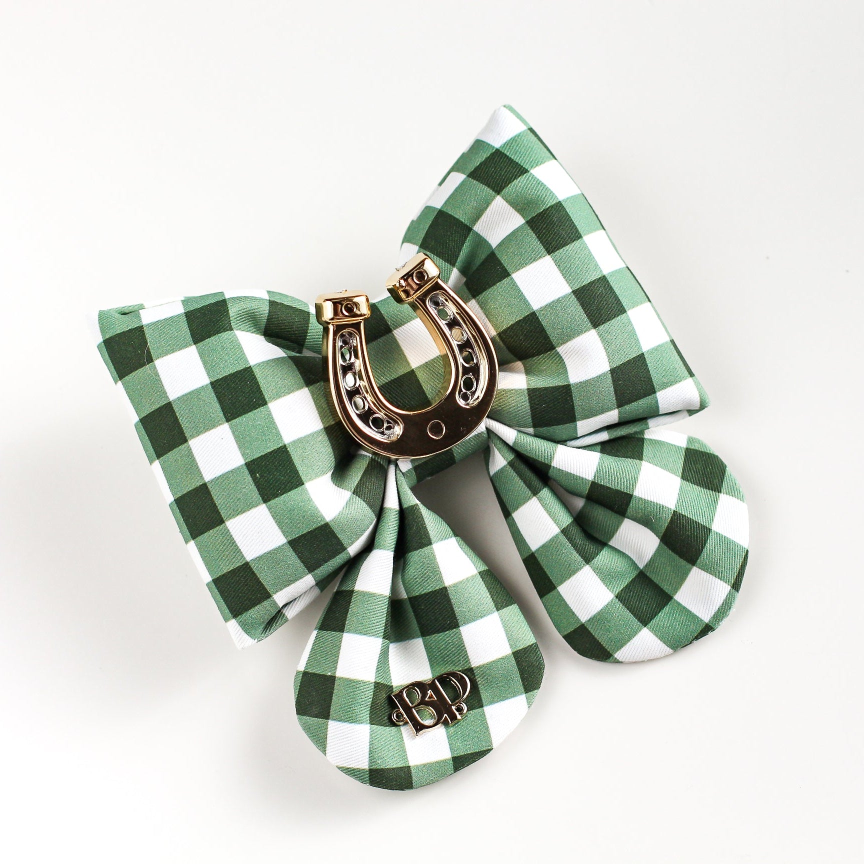 Green and white checkered bow with a gold horseshoe charm on a white background