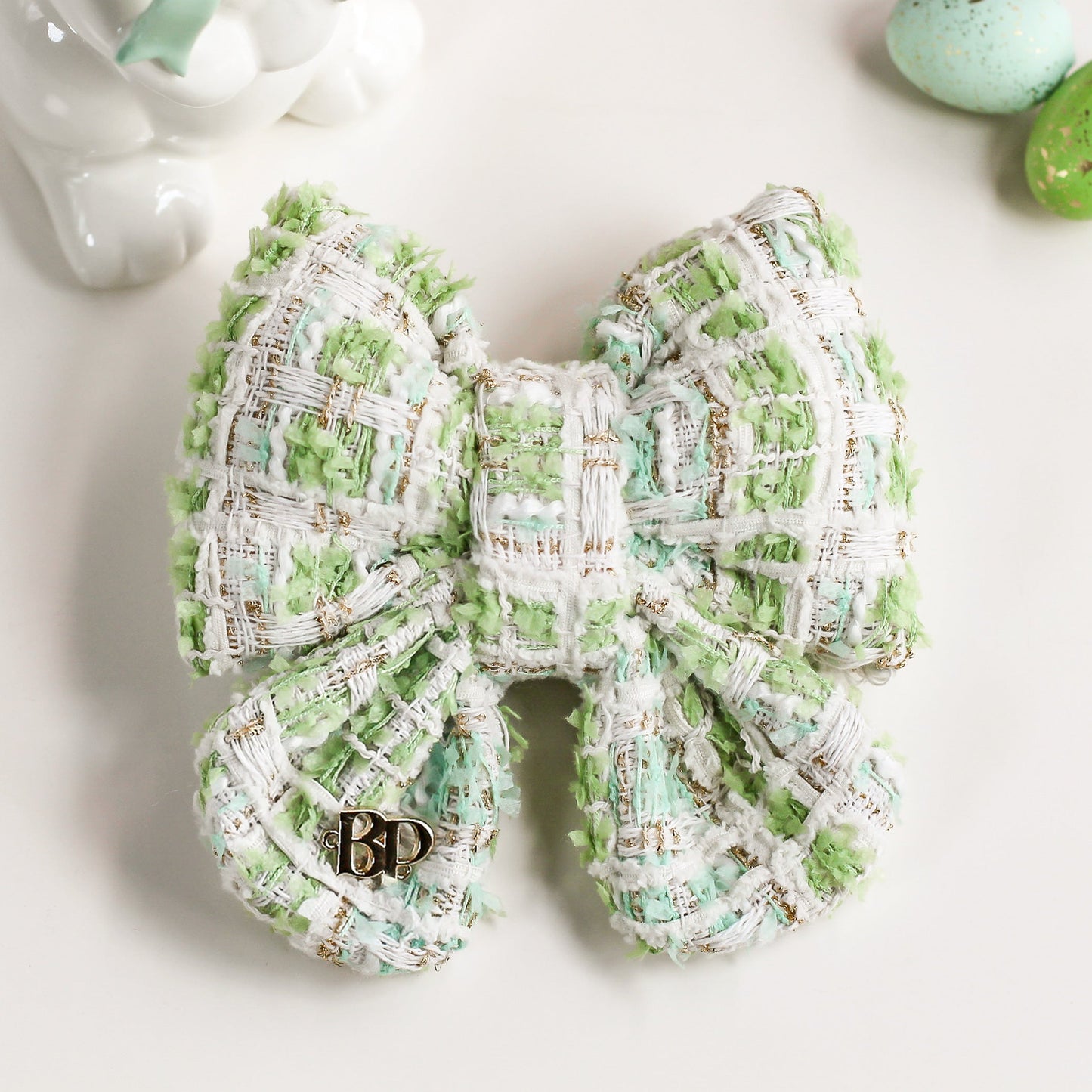 Green and white textured bow with a brand logo on a light background