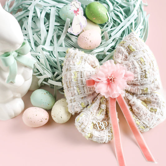 Decorative Easter pink tweed bow with pastel eggs and nest on a pink background