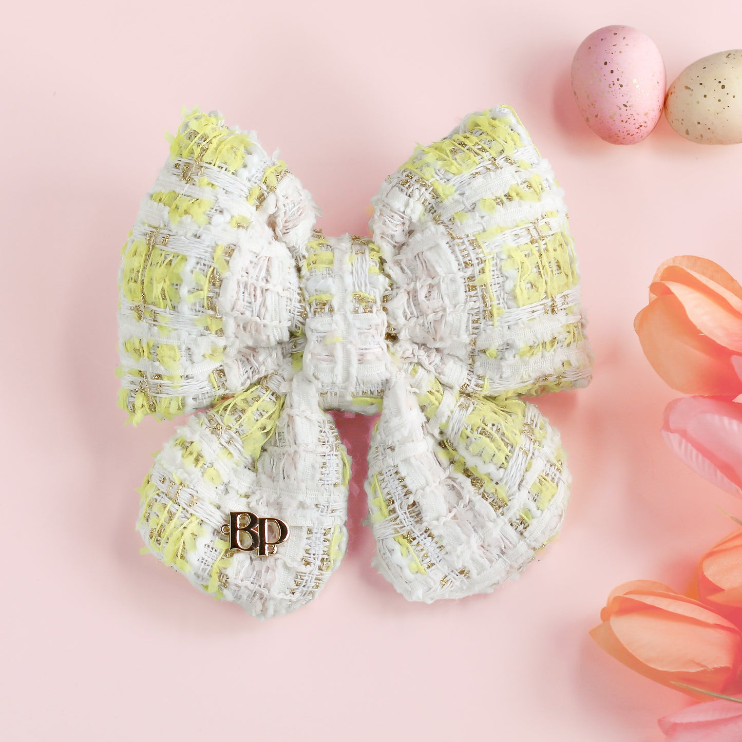 Large decorative bow with yellow and white pattern on a pink background with Easter eggs and flowers.