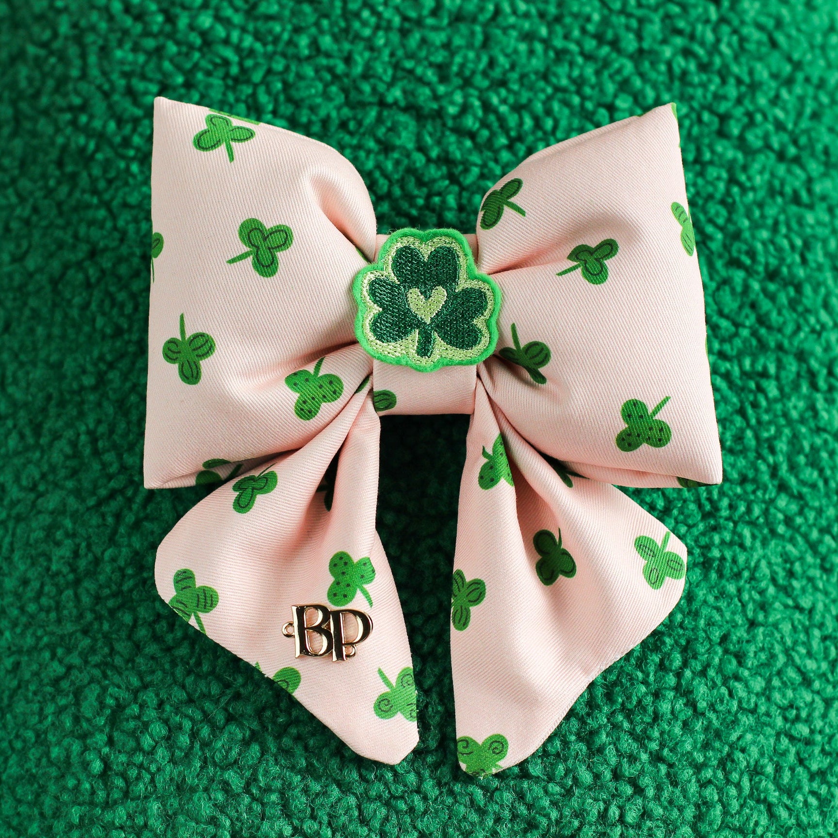 Pink bow with green shamrock pattern on a green textured background