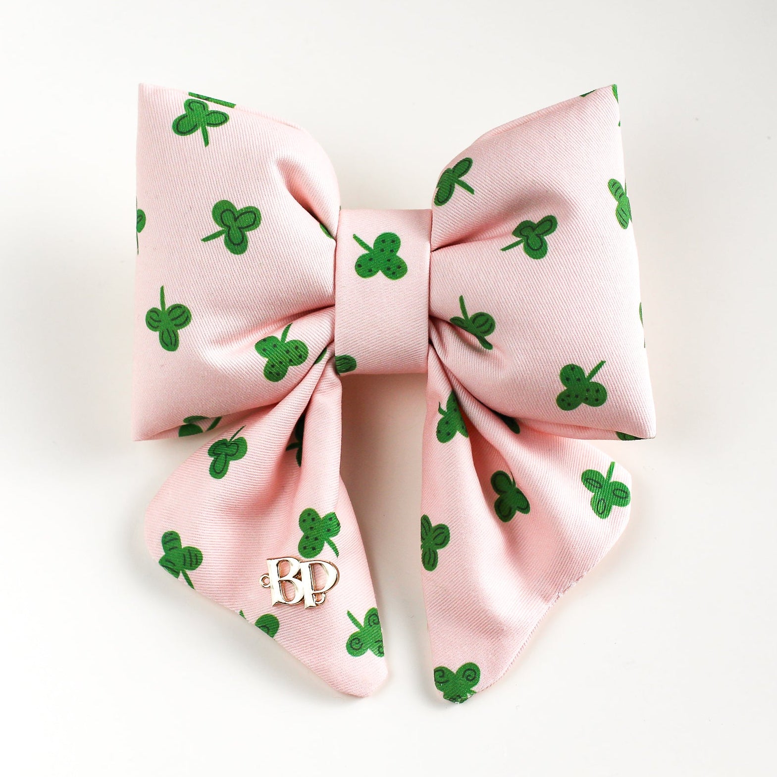 Pink hair bow with green shamrock patterns on a white background