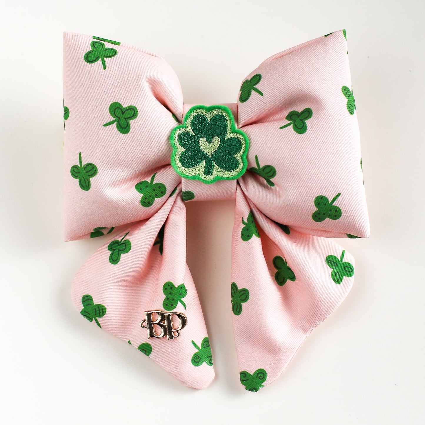 Pink hair bow with green shamrock pattern on a white background