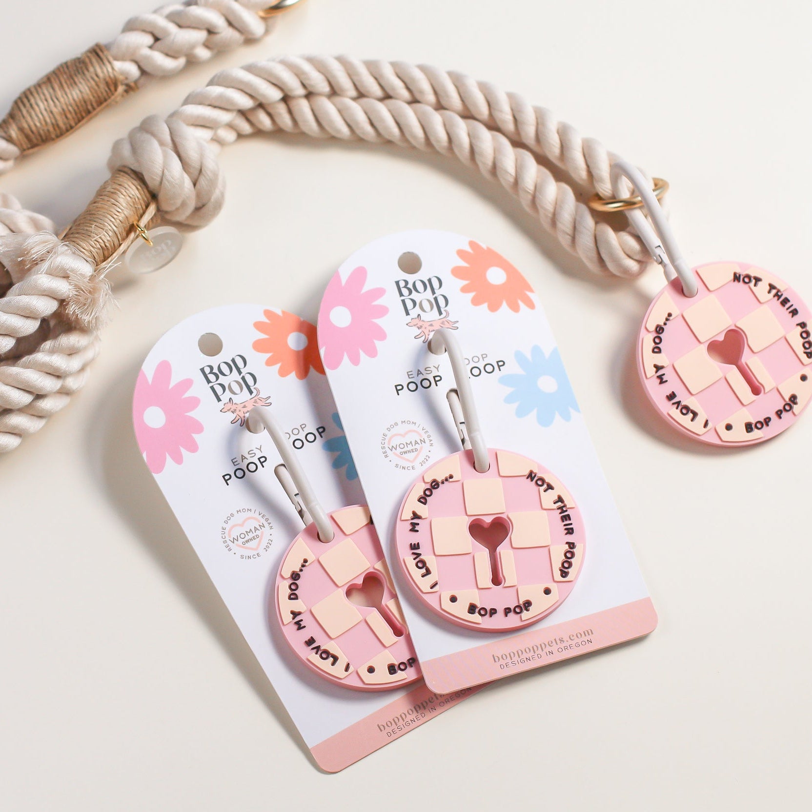 Dog leash with pink checkered poop loop with carabiner design on a white background