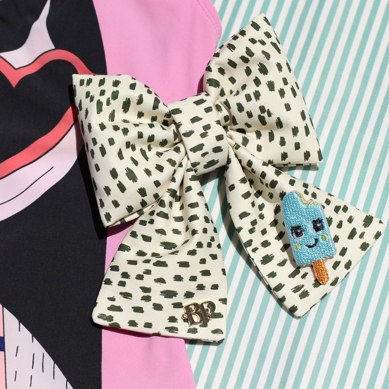 icy pop aqua blue sailor bow with tails in black dotted cotton fabric over mint green stripes background. Modern trendy bows for pets dogs and cats by Bop Pop Pets