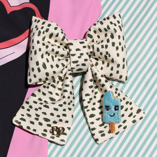 icy pop aqua blue sailor bow with tails in black dotted cotton fabric over mint green stripes background. Modern trendy bows for pets dogs and cats by Bop Pop Pets