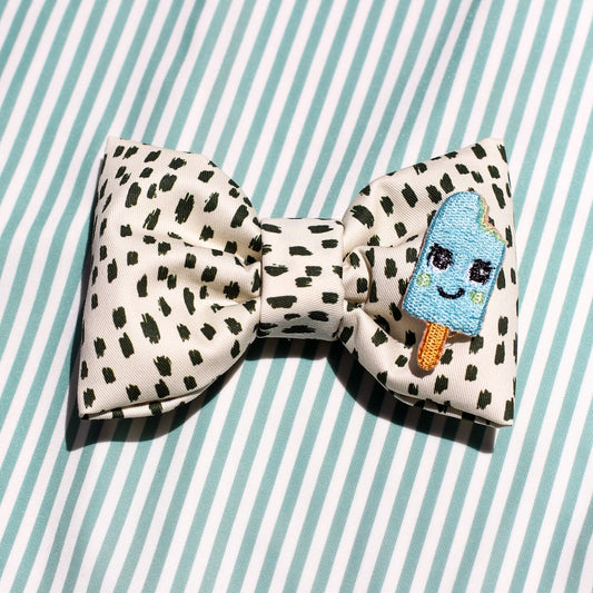 icy pop aqua blue bow tie in black dotted cotton fabric over mint green stripes background. Modern trendy bows for pets dogs and cats by Bop Pop Pets