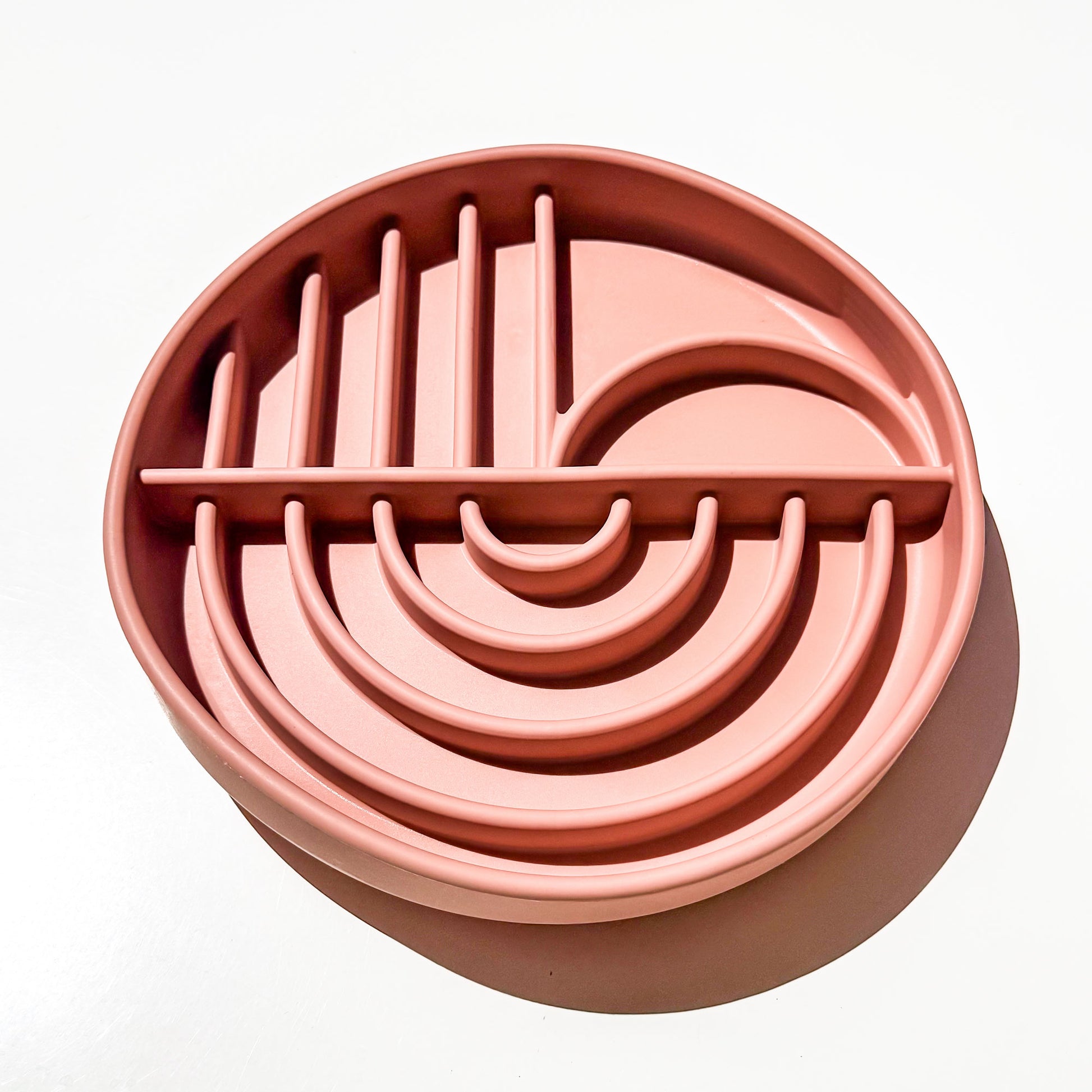 A round, deep dish style  multi-compartment silicone pet slow feeder in a dusty rose pink color, photographed from a top-down angle on a clean white background with a soft shadow.