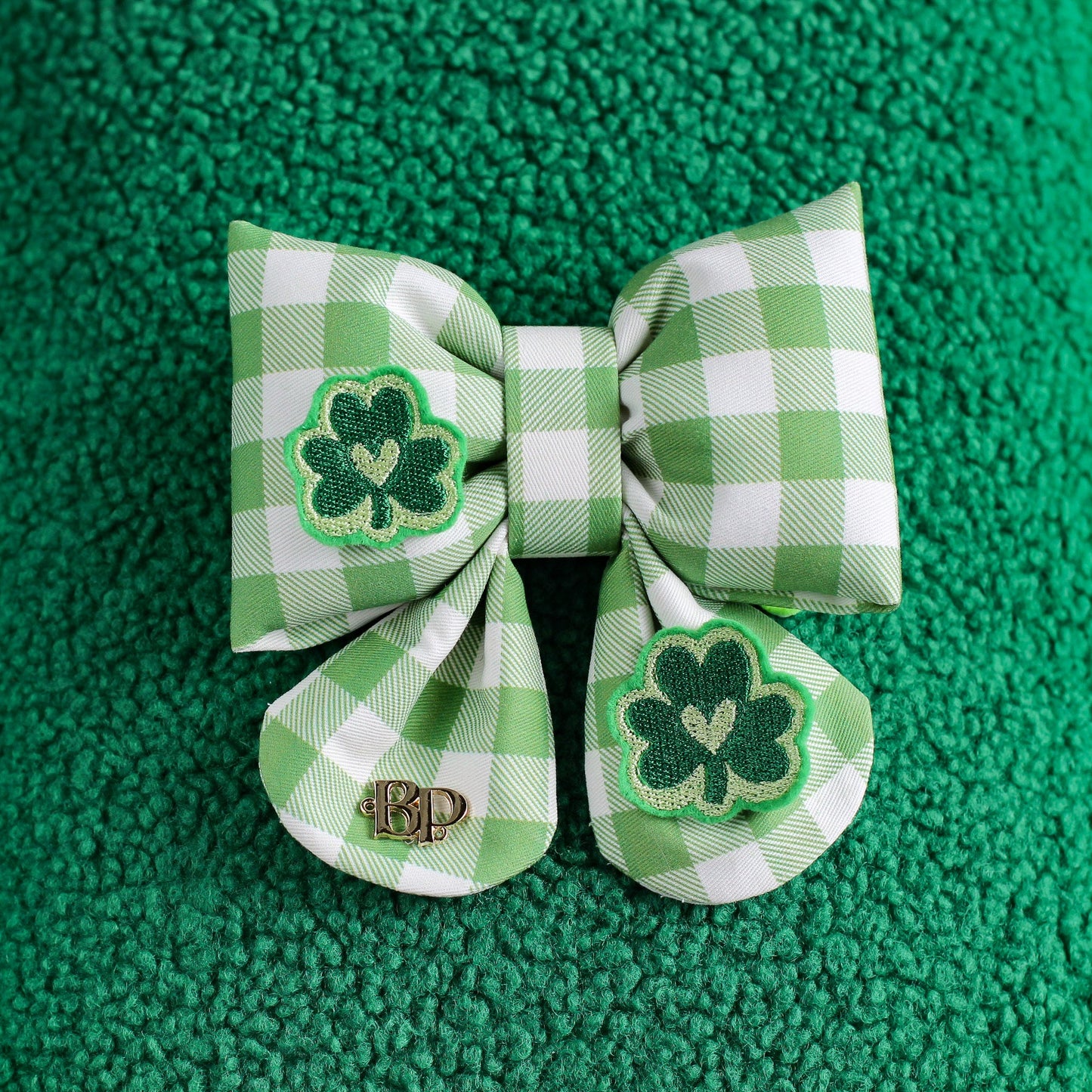 Green checkered bow with shamrock design on a green textured background