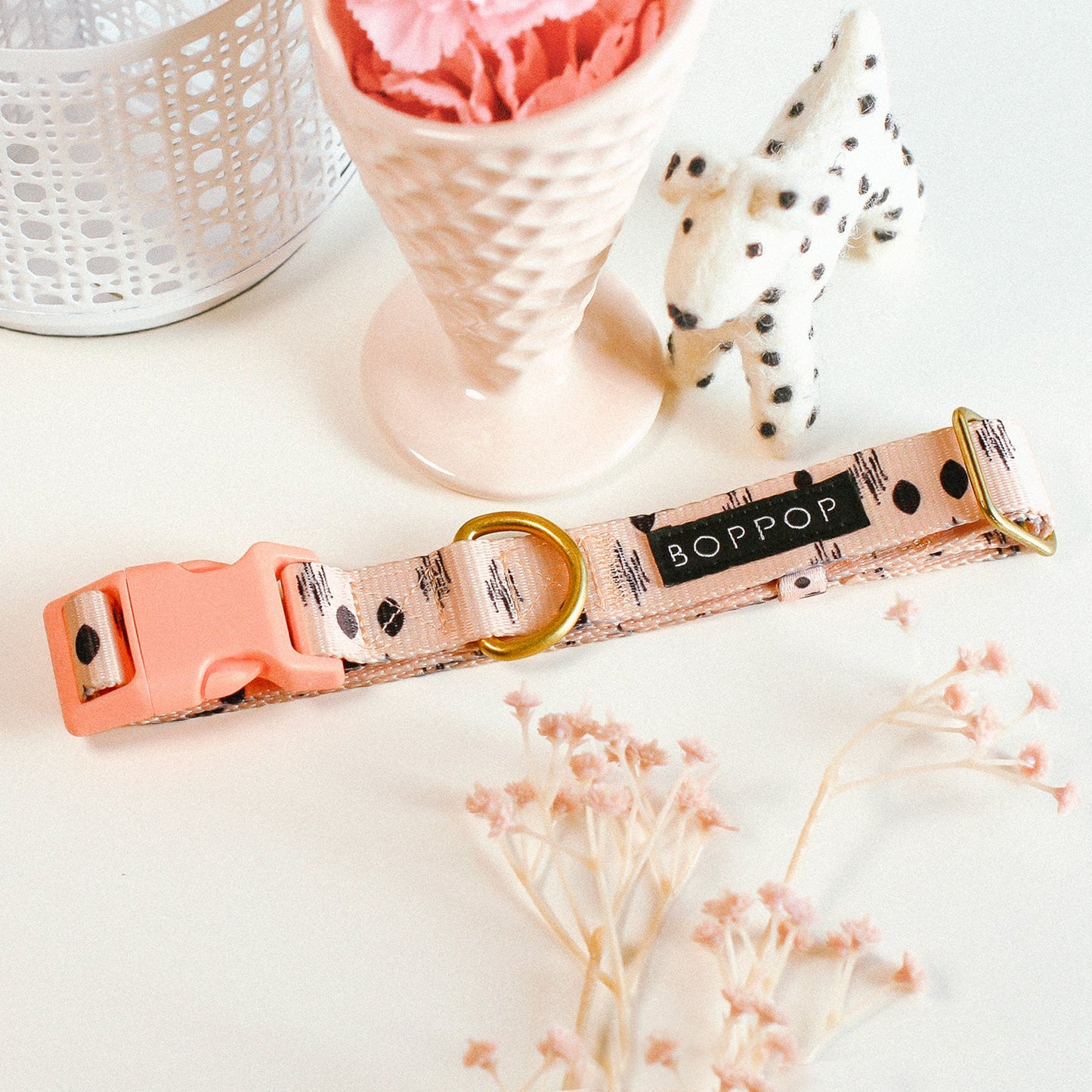 Dog collar with 'BOPPOP' branding on a light surface with decorative elements.