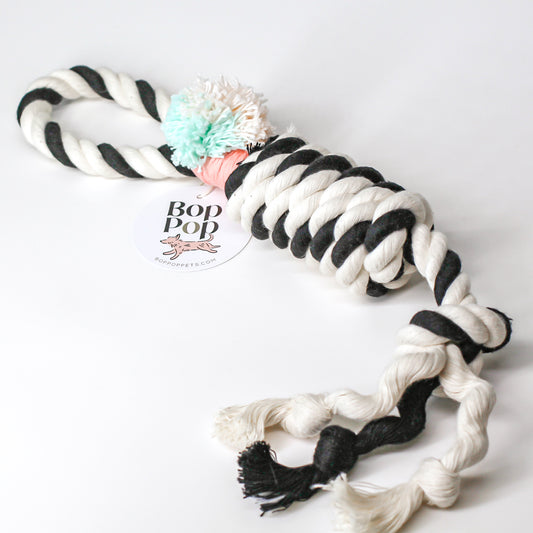 Tuggies dog toy made of 100% cotton rope. Twisted 2 color with handle, pom pom and fringe for interactive, stimulating playtime. Great for all size dogs small medium large. Hand made, tight twisted for tug & toss retrieve. Bop Pop Pets pet dog toy accessories.