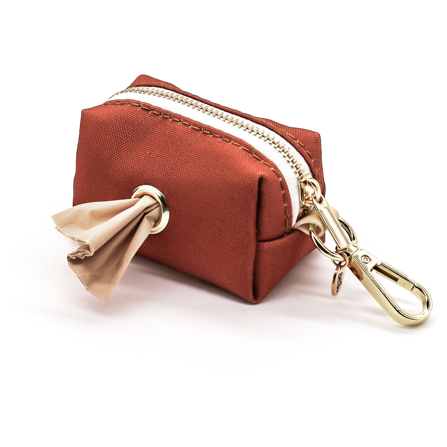 Clay orange brown colored canvas fabric pouch with white zipper  and gold clasp hardware with poop bag sticking out. Poop bag dispenser